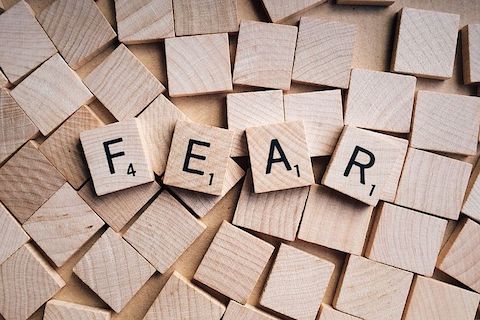 A pile of scrabble pieces where the only ones that are flipped over read FEAR. 