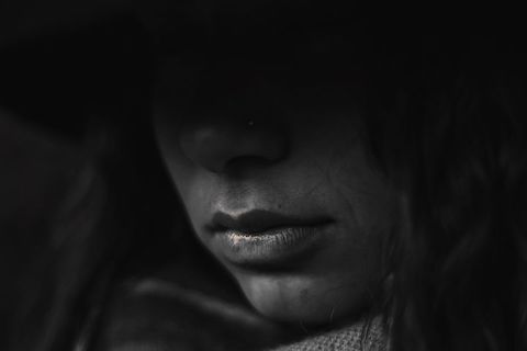 Close up of womans face, heavily shadowed. 