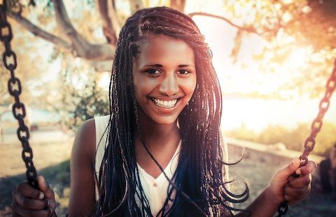 Woman smiling joyfully on a swing set. 