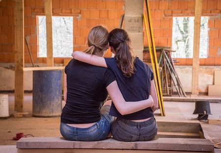 A young couple holding each other in a house that is in mid construction. 