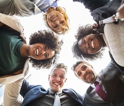 Upward camera angle as 5 people look downward and smile. 