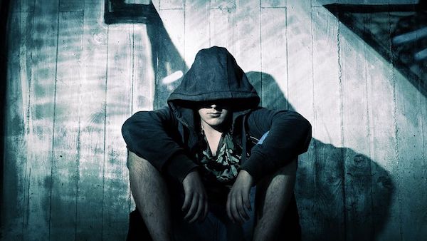 A hooded person sitting menacingly, illustrating evil. 