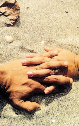 Parent and child holding hands on the sands of a beach. 