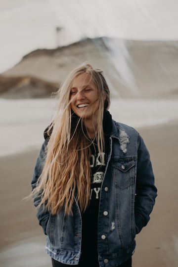 Woman walking on a beach, smiling and expressing happiness. 