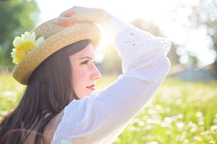 Woman holding the hat on her head, looking onward with content. 