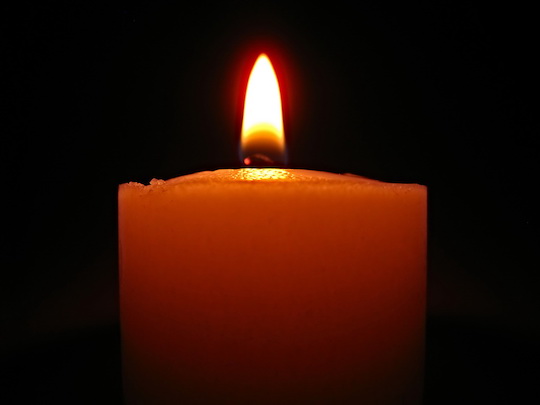 A lone, lit candle with a dark background. 