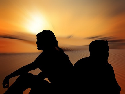 A silhouette of a couple sitting back to back in front of a sunset, expressing conflict. 
