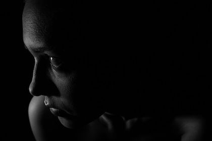 Black and white close up photo of the side of a womans face, she is expressing depression. 