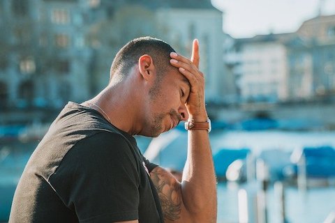 Man holding his palm to his forehead, expressing stress. 