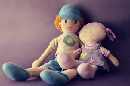 Two Raggedy Anne style dolls placed next to one another, one has blue colors one has pink. 