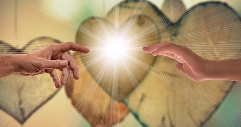 A single male hand with its finger pointing toward a female outreaching hand as light exudes from the space between them in front of multiple hearts. 