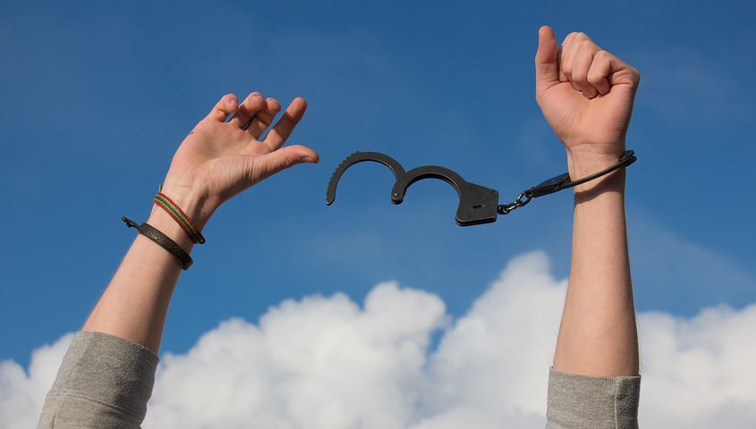 Person breaking their handcuffs, expressing freedom. 