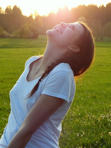 Woman looking toward the sky and joyfully laughing. 
