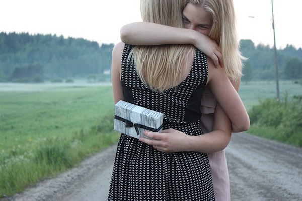 Two women hugging one another, one has a gift, expressing kindness. 