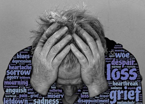 A black and white picture of a man holding his head in his hands. There are blue colored words that express negativity and pain. Sadness, heartache, sorrow, mourning, etc. 