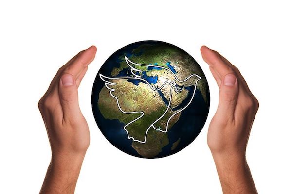 A person holding a globe of earth between their hands, two doves are illustrated on the surface. 
