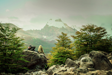 Hiker relaxing on a rock as they view a far away mountain. 