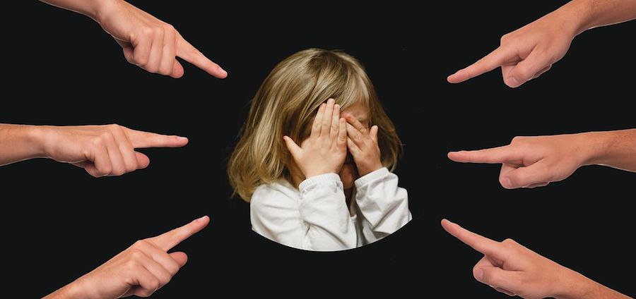 Six different hands pointing their fingers at a little girl who is crying, illustrating projection. 