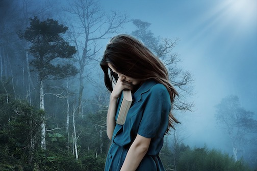 Woman clinching a book close to her chest, expressing sadness. 