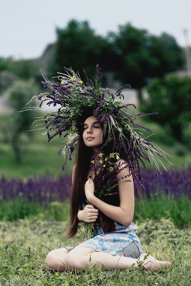 A peaceful woman standing with a head dress made of lavender. 