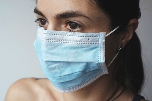 Close up picture of a woman wearing a disposable face mask. 